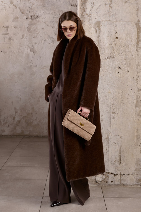 Woman wears an elegant longline coat with large oversized pockets and a wide collar and lapels, paired with an optional thick faux fur belt that cinches the waist, adding chic definition to the relaxed fit.