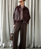 Model wearing dark burgundy leather jacket with gold hardware, exuding modern elegance and fashion-forward style.