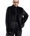 Model wearing a short black mink fur coat, styled with dark jeans and a handbag, showcasing elegant winter fashion.