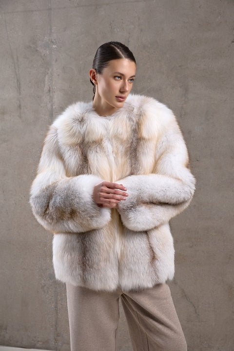 A woman exudes sophistication in a full-bodied fox fur coat featuring golden cross tones, designed for elegance and resilience against harsh climates.