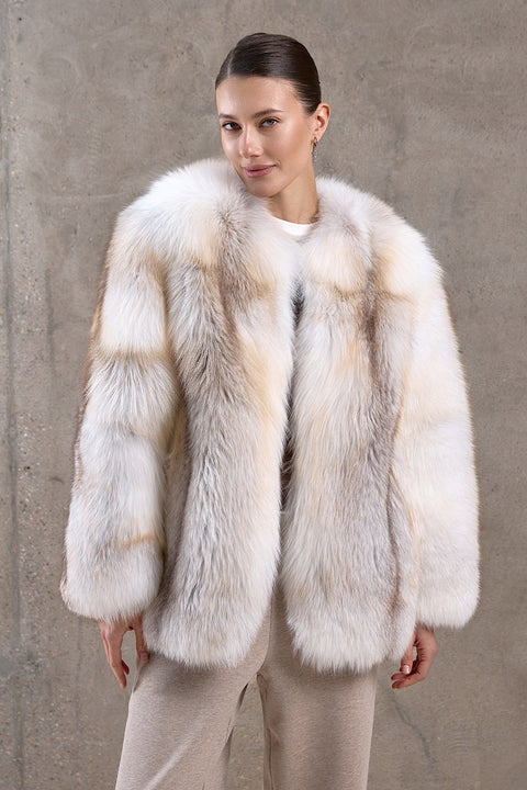 A woman is wearing a stunning gold crossed fox fur coat with a full pelt design, radiating glamour and built to withstand freezing arctic temperatures.