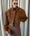 A woman wearing a cropped bomber jacket crafted from ultra-soft genuine suede in a rich whiskey hue, featuring a modern waist-length silhouette that blends timeless appeal with contemporary edge.