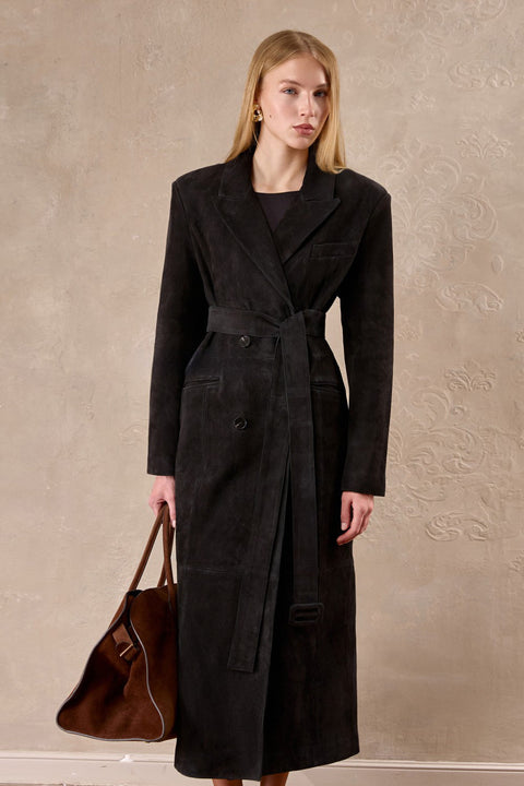 Dressed in an espresso-hued suede coat, a woman exudes confidence with its sculpted silhouette and refined structure.